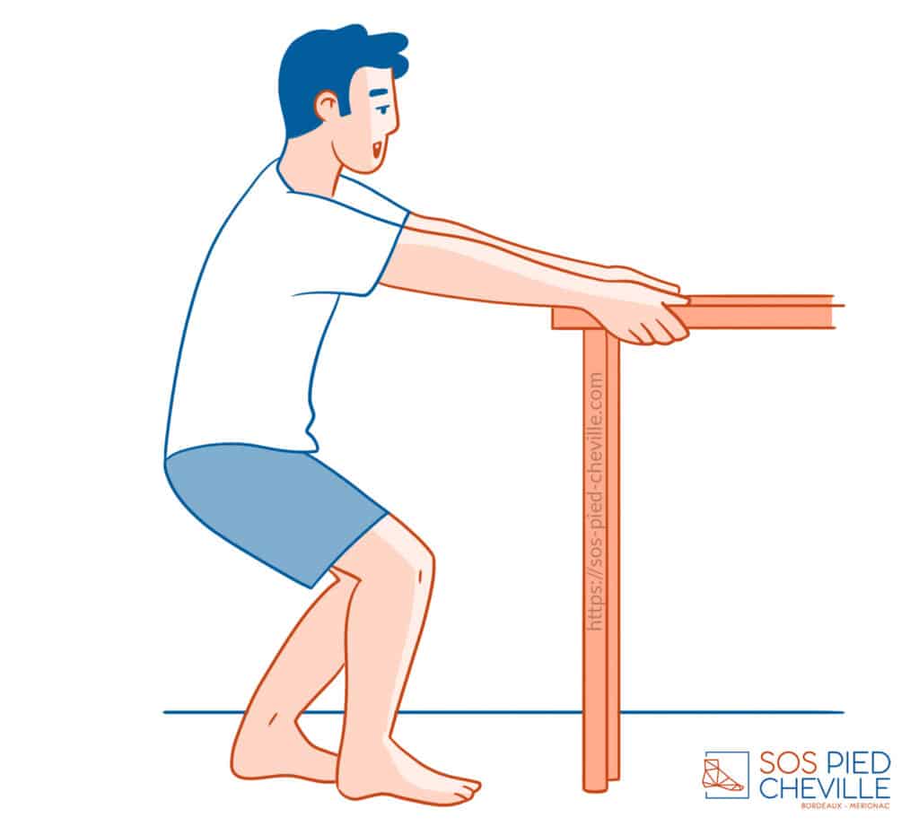 Homme en appui des mains sur une table, genoux fléchis et talons au sol, pour étirer la chaîne postérieure de la jambe